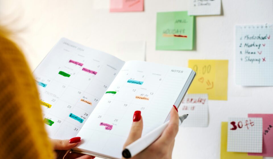 Person holding an open planner filled with notes and appointments