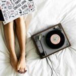 Woman relaxing on her bed while listening to music in a calm, clean bedroom.