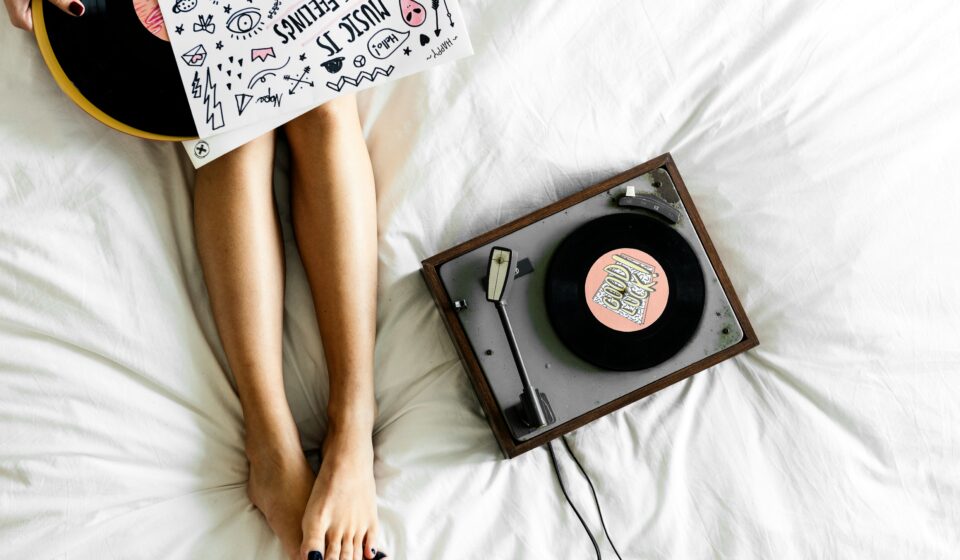 Woman relaxing on her bed while listening to music in a calm, clean bedroom.