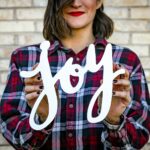 Person holding a small sign with the word joy written on it