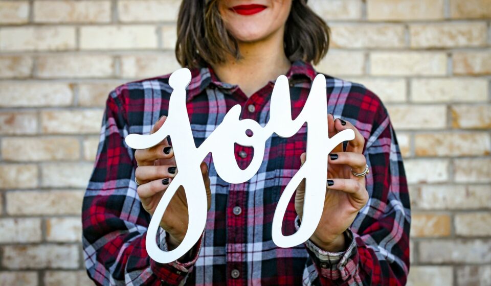 Person holding a small sign with the word joy written on it