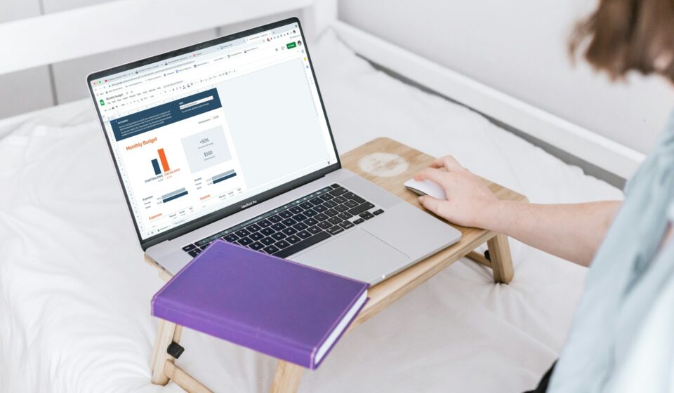 Person using a laptop while sitting on a bed in a calm home setting