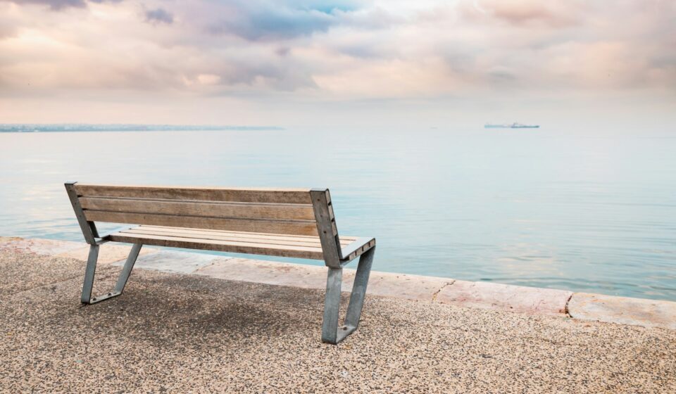 A quiet bench overlooking calm water on an open embankment