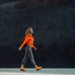 Woman walking calmly outdoors with a gym bag, representing steady personal growth