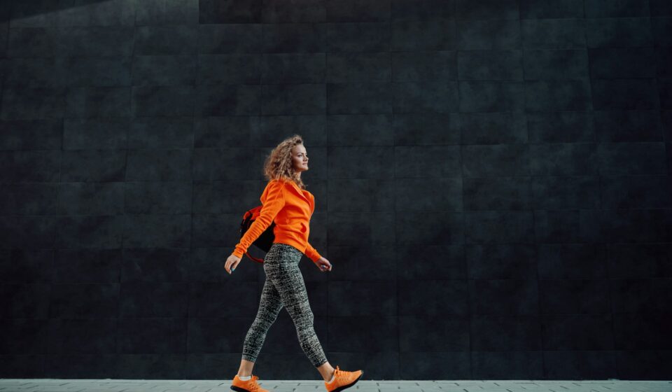 Woman walking calmly outdoors with a gym bag, representing steady personal growth