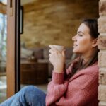 A busy woman enjoying a calm morning coffee at home, reflecting simple and realistic wellness through everyday self-care.