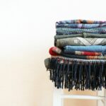 Clothes piled on a small white wooden stool in a simple room