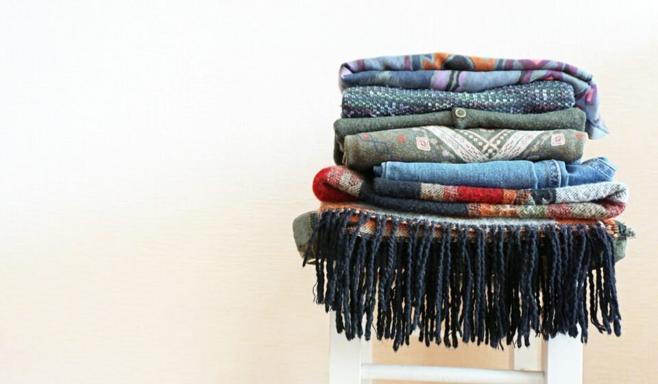 Clothes piled on a small white wooden stool in a simple room
