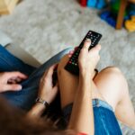 A couple sitting together on a couch watching television at home