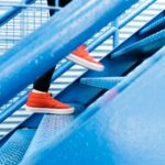 A person stepping onto blue stairs, showing everyday movement without a gym setting.