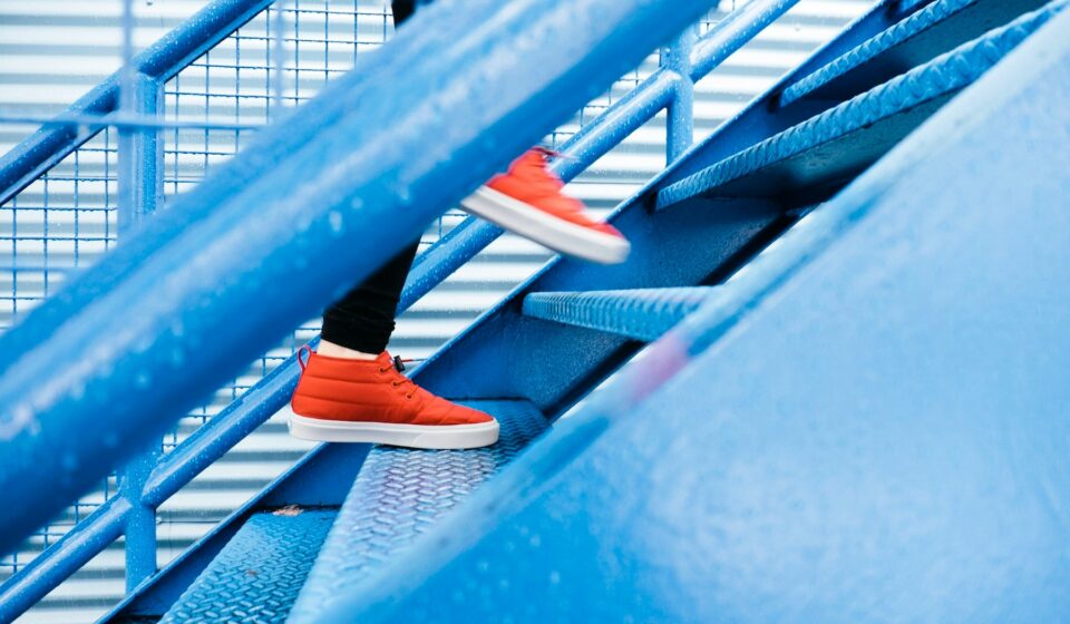A person stepping onto blue stairs, showing everyday movement without a gym setting.