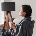 Woman sitting quietly in a sunlit room with natural light coming through a window