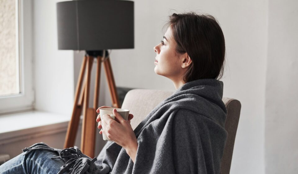 Woman sitting quietly in a sunlit room with natural light coming through a window