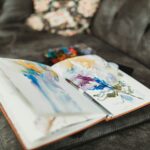 Watercolor journal and paintbrush resting on a couch