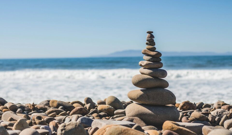 Stacked stones on a quiet shoreline, symbolizing balance and steadiness in everyday life