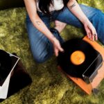 Person placing a vinyl record on a turntable in a softly lit room