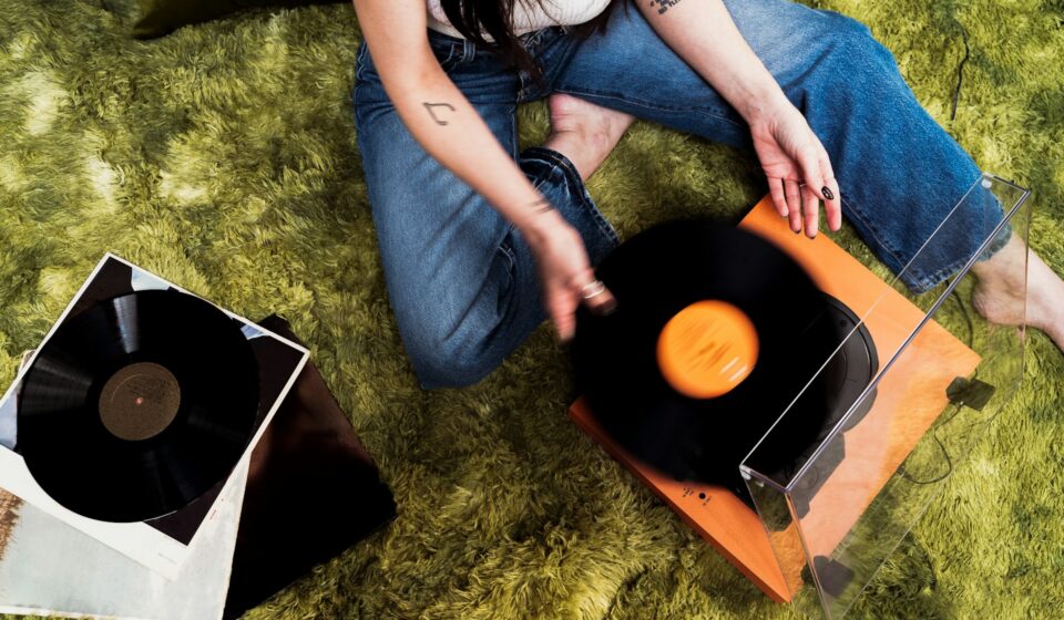 Person placing a vinyl record on a turntable in a softly lit room