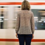 Rear view of a woman standing on a train platform as a train moves past