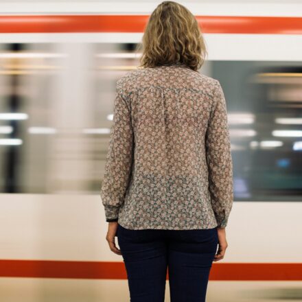 Rear view of a woman standing on a train platform as a train moves past