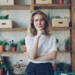 Young woman with hand on chin looking thoughtful while hesitating over a decision