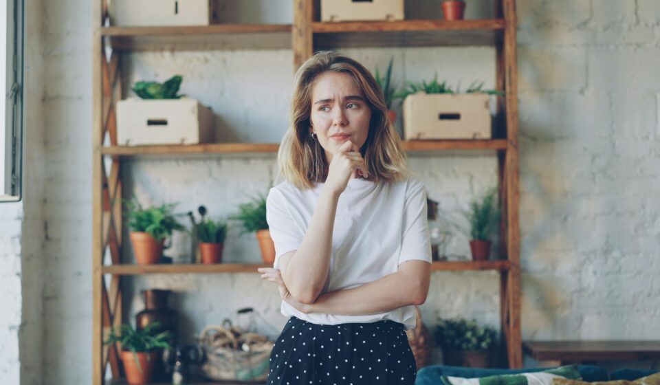 Young woman with hand on chin looking thoughtful while hesitating over a decision