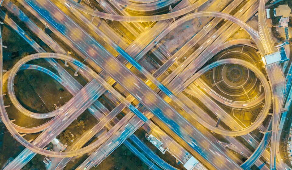 Aerial view of a complex highway intersection with multiple lanes and traffic flow at dusk