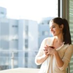 Young woman relaxing on a balcony with a cup of coffee, enjoying a quiet moment during the day