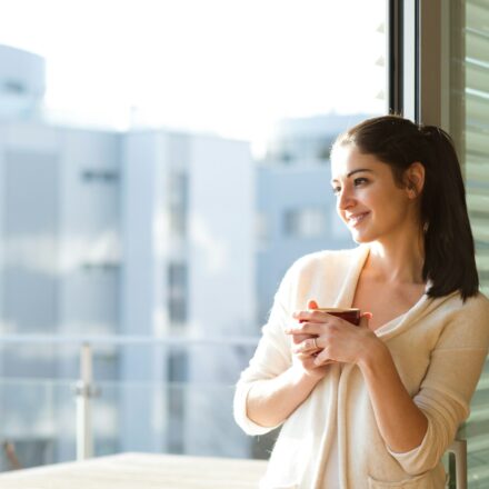 Young woman relaxing on a balcony with a cup of coffee, enjoying a quiet moment during the day