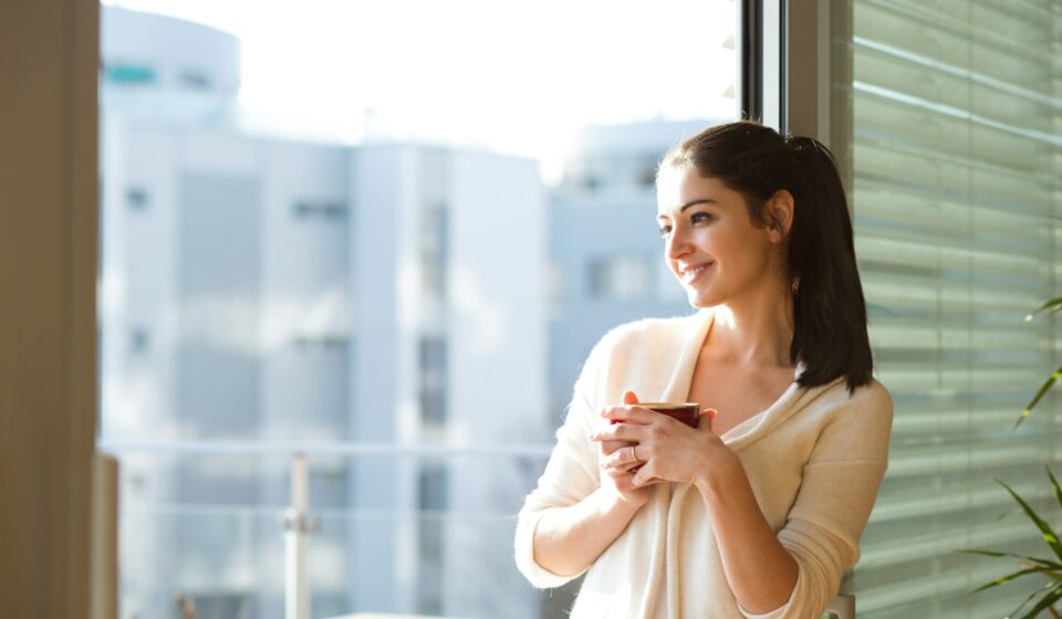 Young woman relaxing on a balcony with a cup of coffee, enjoying a quiet moment during the day