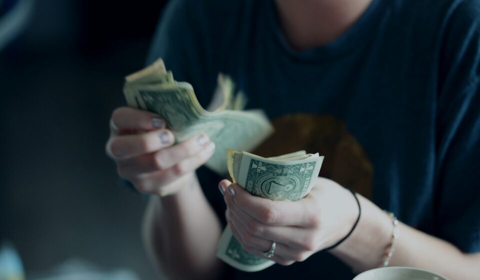 Hands counting cash in a quiet moment, representing everyday financial decisions and stress