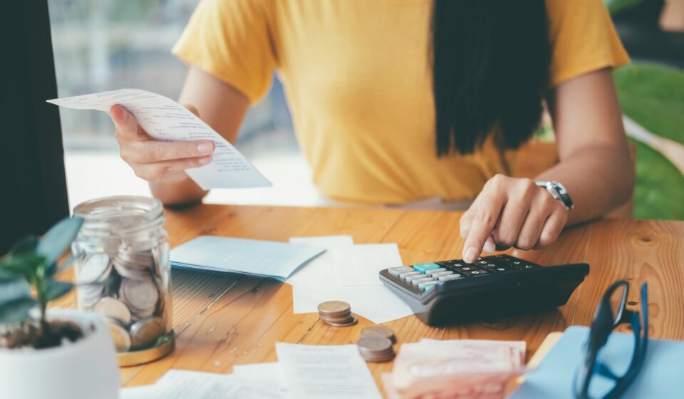 Person organizing cash and calculating expenses, representing small steps to manage financial stress