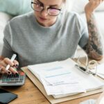Woman sitting at home reviewing bills, representing everyday financial overwhelm and decision-making