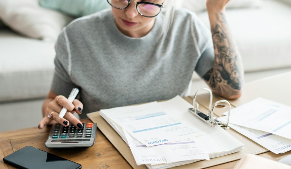 Woman sitting at home reviewing bills, representing everyday financial overwhelm and decision-making