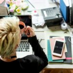 Hands holding a coffee cup beside a laptop during a quiet work moment at a desk