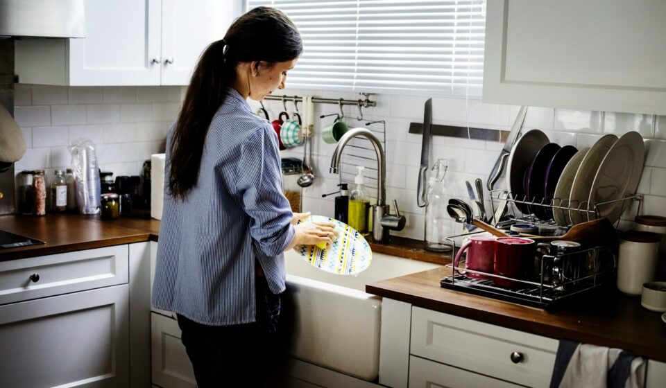 Woman washing dishes in a kitchen after a meal