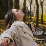 Woman relaxing on a park bench surrounded by autumn trees during a quiet moment outdoors