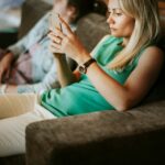 Woman relaxing on a couch while looking at updates on her smartphone