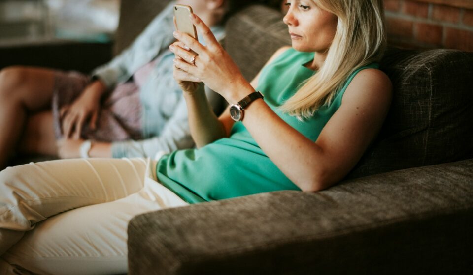 Woman relaxing on a couch while looking at updates on her smartphone