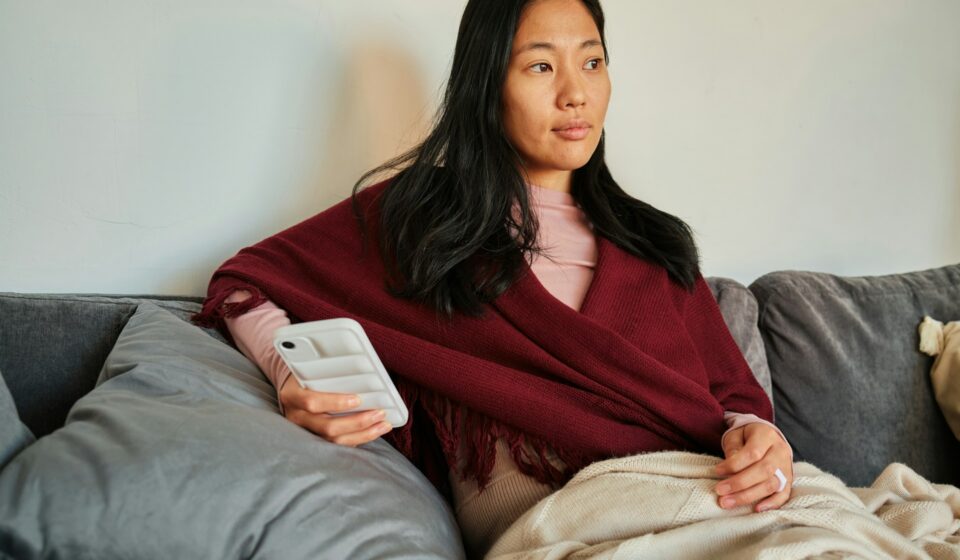 Woman sitting on a couch looking at her phone while reading news or social media updates
