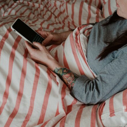 Person lying on a bed using a smartphone while losing track of time scrolling