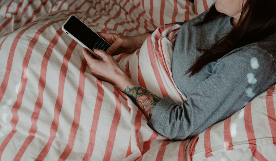Person lying on a bed using a smartphone while losing track of time scrolling