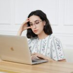 Woman sitting in front of a laptop looking tired while working at home