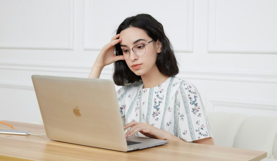Woman sitting in front of a laptop looking tired while working at home