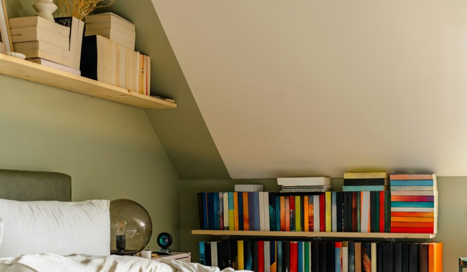 Cozy bedroom with bookshelves, bed, and personal items creating a visually busy living space