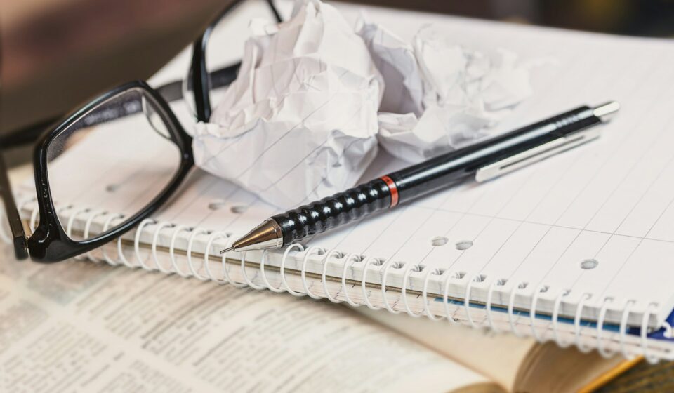 Black-framed eyeglasses resting on a page with blurred text, representing difficulty focusing and mental fog.